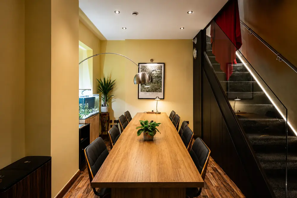 The creative workspace — desks along the table, Van Gogh print and staircase light